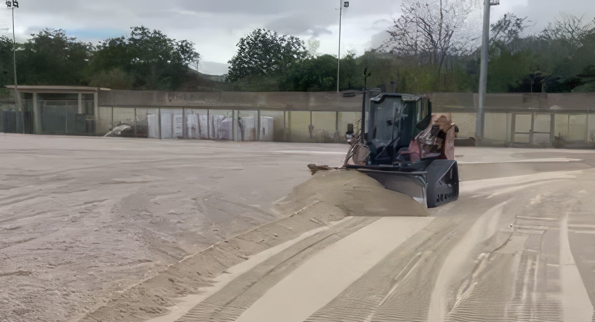 Dozer che livella un campo sportivo, tracce parallele sulla sabbia