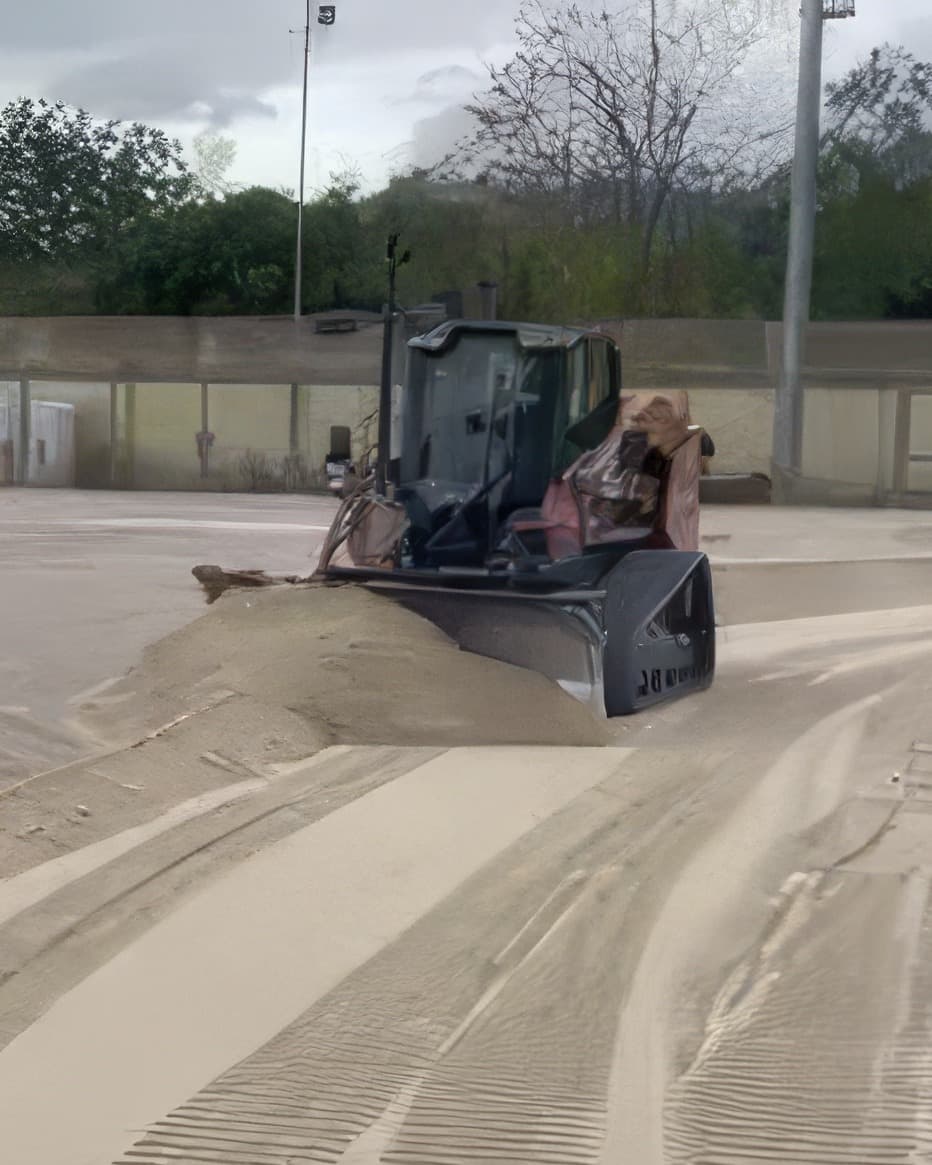 Dozer che livella un campo sportivo, tracce parallele sulla sabbia